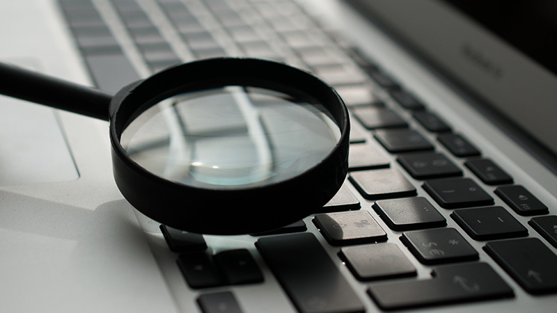 Magnifying glass near a laptop keyboard.