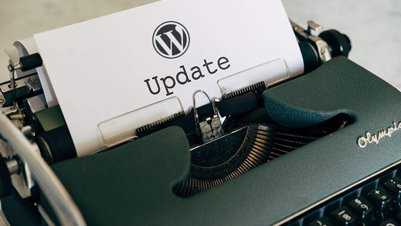 Typewriter and a white sheet containing the WordPress logo and the word "update".