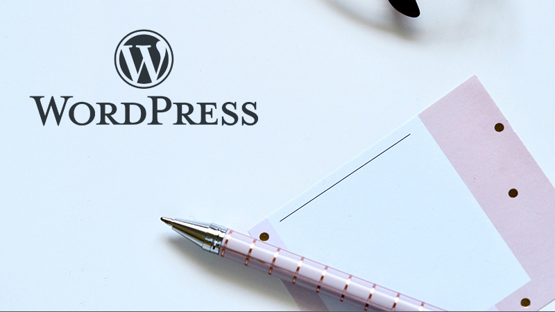 WordPress logo near a paper and a pen.
