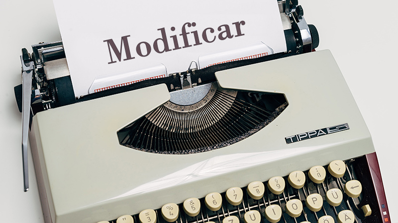 Typewriter and a white sheet containing the word "Modify".